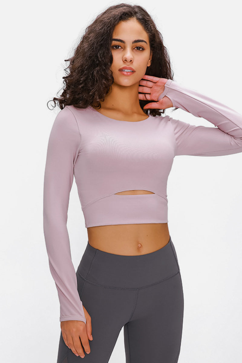 Woman wearing a long-sleeved, cropped workout top in lilac, fitted with a support strap, for high-impact activewear.