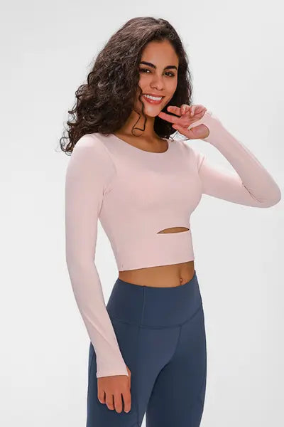 Woman wearing a long-sleeved, cropped workout top in pink, fitted with a support strap, for high-impact activewear.